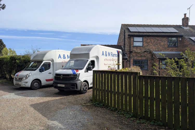 2 x A&M Removals vans parked outside a house