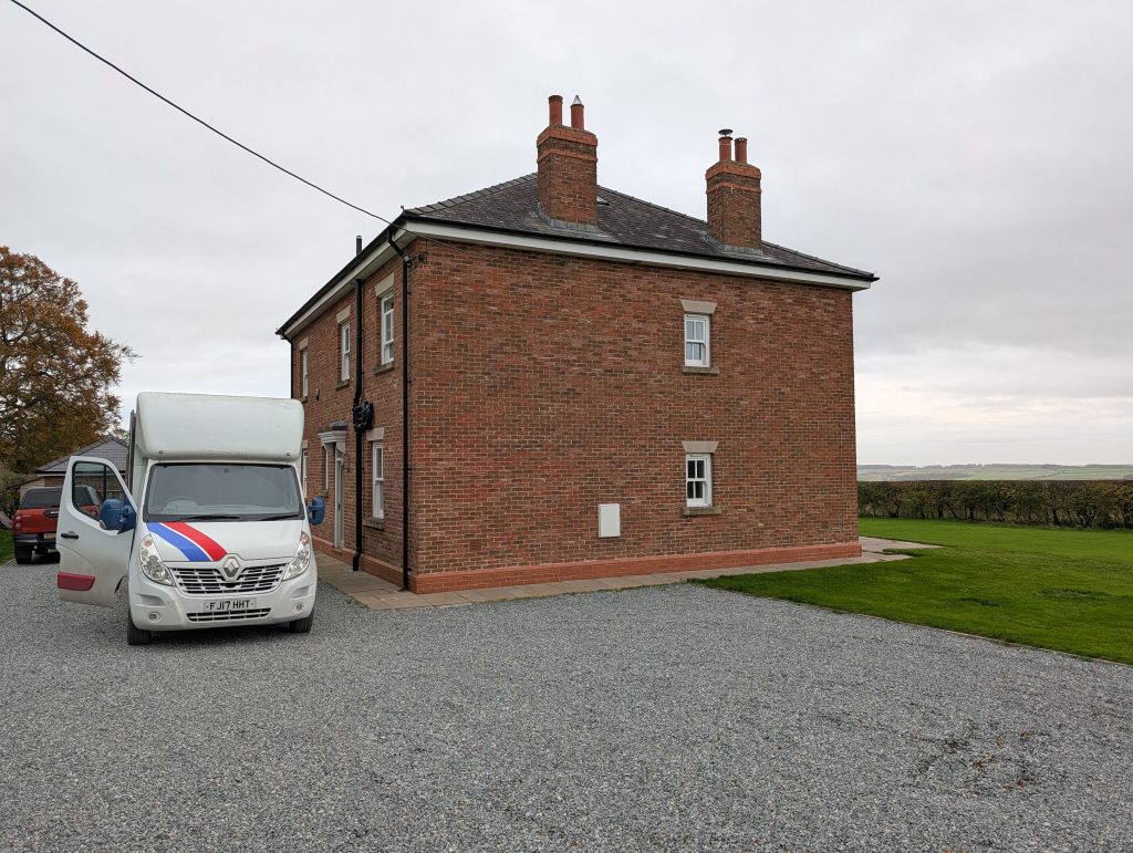 A removals van outside a large detached house in a rural location